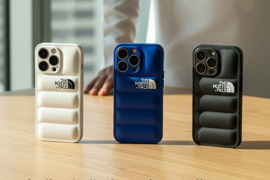 Man in a white traditional outfit standing behind three phone cases on a table with a cityscape in the background.