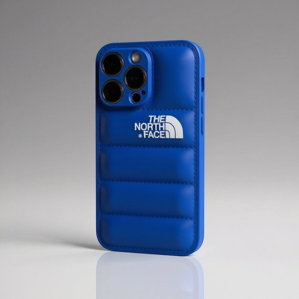 The North Face blue silicone iPhone case with quilted design and white logo. Protects phone from scratches and bumps.