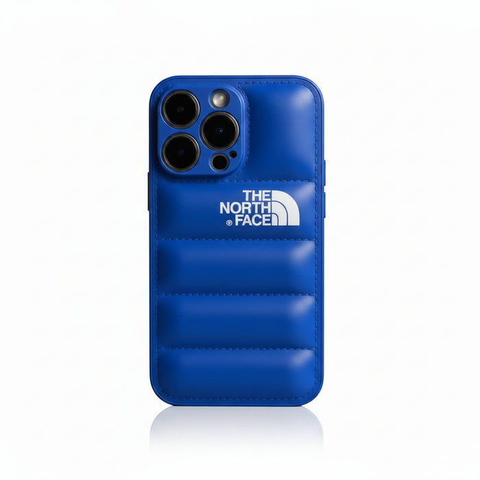 The North Face blue silicone iPhone case with quilted design and white logo. Protects phone from scratches and bumps.