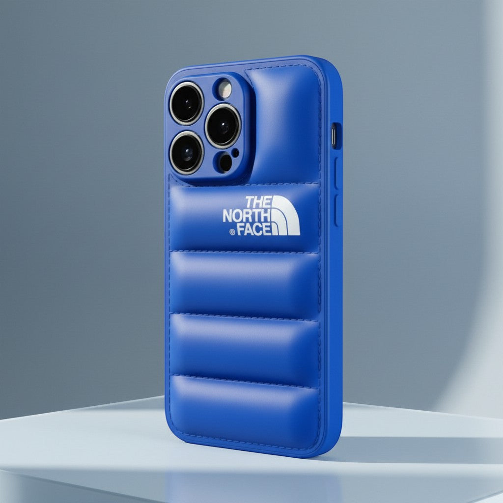 The North Face blue silicone iPhone case with quilted design and white logo. Protects phone from scratches and bumps.